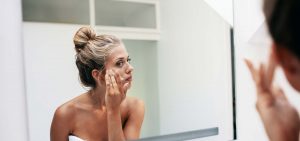 Woman Looking at Her Face in Mirror