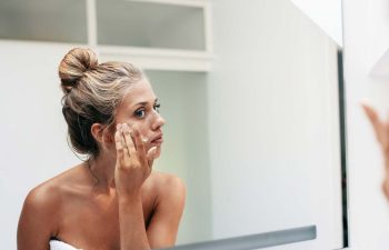 Woman Looking at Her Face in Mirror